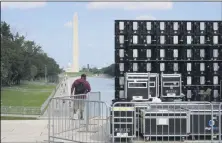  ?? JACQUELYN MARTIN — THE ASSOCIATED PRESS ?? With the Washington Monument in the background, people walk by equipment being set up near the reflection pool on Thursday Aug. 27, in Washington, prior to the March on Washington, which is being held on Friday at the Lincoln Memorial.