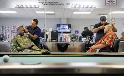  ?? DAVID GOLDMAN — THE ASSOCIATED PRESS ?? Former NFL football player Vonta Leach, left, who voted for Hillary Clinton, gets his haircut alongside Jamie Locklear, who voted for Donald Trump, at a barbershop in Lumberton, N.C., Thursday, Oct. 26, 2017. Leach has no problem with Trump’s...