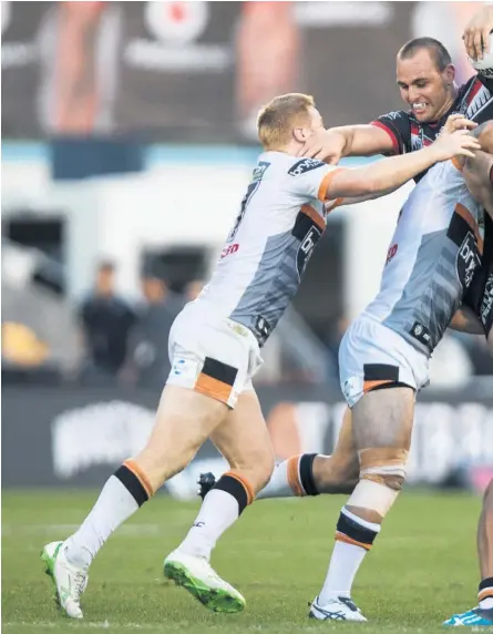  ??  ?? Warriors forward Simon Mannering is caught in a tackle by the Wests Tigers defence during yesterday’s make or break