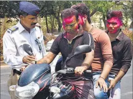  ?? PHOTOS: BACHCHAN KUMAR ?? Police stop a biker on Palm Beach Road on Thursday. (Right) A resident of Nerul plays Holi.