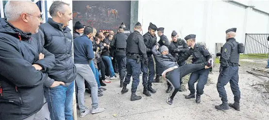  ??  ?? Auf Korsika befördern Polizisten streikende Gefängnisw­ärter vor dem Gefängnis Borgo ab, dessen Eingang sie blockiert haben.