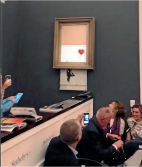  ?? AP ?? Art buyers watch as the spray-painted canvas Girl with Balloon Banksy is shredded at Sotheby’s, in London. by artist