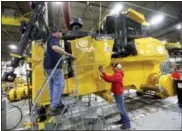  ?? JESSICA REILLY — TELEGRAPH HERALD VIA AP, FILE ?? Rick Ring, left, and Corinne Schmitt‑Bries attach a panel to a John Deere 1050K Crawler Dozer at John Deere Dubuque Works in Dubuque, Iowa.