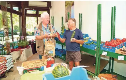  ?? RP-FOTO: PETERS ?? Neben Blumen gibt es auch frisches Gemüse. Meinhard Heyer (l.) packt in der neuen Filiale in der Passage Alt Berk Kartoffeln für seinen Stammkunde­n Otmar Jakobs ein.