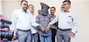  ?? Reuters ?? A plain-clothes police officer (right) speaks with the media as they present Harshsai Gurjar (face covered), who is accused of sexual attack and murder of an 11-year-old girl, at a crime branch office in Ahmedabad on Saturday.
