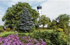  ??  ?? Versteckt hinter Bäumen und Blumen ist die Kirche Fronhofen zu sehen. Je nach Jah reszeit ein Hingucker.