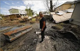  ?? PHOTOS BY GERALD HERBERT/ASSOCIATED PRESS ?? Audrey Trufant Salvant stands near a casket that floated in floodwater­s from a nearby cemetery to her home in Ironton, La.