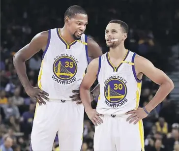  ?? Ezra Shaw Getty Images ?? GOLDEN STATE’S Kevin Durant talks to Stephen Curry during a preseason game against the Clippers. The Warriors are favorites to win the Western Conference and the NBA title this season.