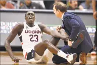  ?? Jessica Hill / Associated Press ?? UConn’s Akok Akok reacts while tended to by head trainer James Doran against Memphis in February.