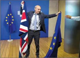  ?? AP/VIRGINIA MAYO ?? A worker changes the European Union and British flags Monday in Brussels before EU negotiator Michel Barnier and British secretary of state for exiting the European Union, David Davis, arrive for the first day of talks on Britain’s withdrawal from the...