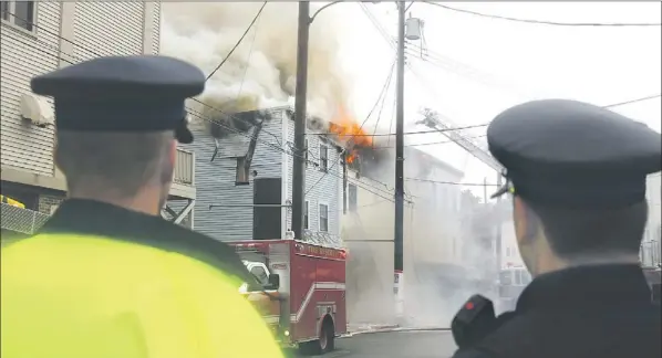  ?? — Photo by James Mcleod/the Telegram ?? A pair of RNC officers watch as a block of buildings burns Wednesday morning in downtown St. John’s. Police were on the scene to assist and keep crowds of onlookers back from the fire as it burned for most of the day.