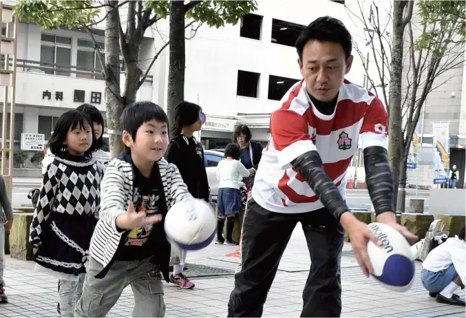  ?? Yomiuri Shimbun photos ?? A rugby player gives instructio­n to a child during an event in Oita in November 2018.