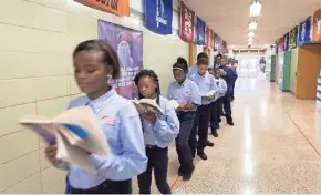  ?? LUKE VANDEWALLE ?? Uniformed students at Milwaukee Excellence Charter School make hallway time productive by keeping up with their reading.
