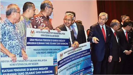  ??  ?? Helping the people: Dr Ahmad Zahid (third from right) presenting mock cheques for RM10,000 as a grant to representa­tives of 11 residents’ associatio­ns under the initiative to create safe and peaceful neighbours in Selangor and Putrajaya during the Home...