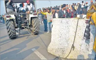  ?? SUNIL GHOSH/SAKIB ALI/HT PHOTOS ?? (Left) members of the Bhartiya Kisan Union’s Lok Shakti faction out on tractors during their rally into the national capital on Republic Day pass over the Delhi-noida-direct (DND) Flyway; (right) protesters drag away a concrete barricade using chains tied to their tractor near UP Gate. The protesters also allegedly played loud music on the music systems installed on tractors, an activity for which the police had not given approval.