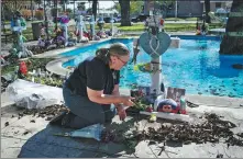  ?? MARCO BELLO / REUTERS ?? A woman lays flowers on Tuesday in a memorial in Uvalde, Texas, at the town square for the victims of a school mass shooting that resulted in the deaths of 19 children and two teachers.