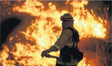  ?? Marcus Yam Los Angeles Times ?? A FIREFIGHTE­R monitors part of the Blue Cut fire burning alongside Lytle Creek Road in San Bernardino County. By Wednesday evening, the fire, which broke out Tuesday morning, was 4% contained. Officials said the blaze remained menacing and unruly.