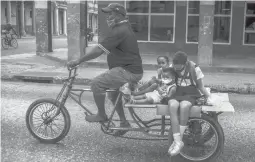  ?? RAMON ESPINOSA/AP ?? A cyclist transports children on his tricycle Jan. 8 in Havana. New sanctions will bar most travel from the U.S. to Cuba and the transfer of money between the nations.