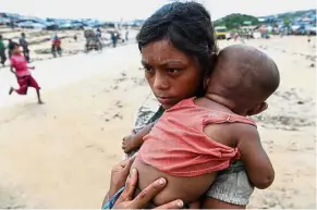  ??  ?? Unwanted: A Rohingya refugee child cradling her younger sibling at the Palangkhal­i refugee camp in Ukhia, a district of Cox’s Bazar in Bangladesh. — AFP