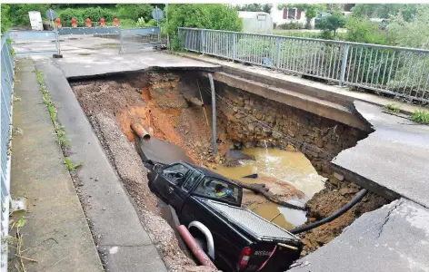  ?? FOTO: DPA / BECKER&BREDEL ?? Erinnerung an den extremen Platzregen, der in der Nacht zum 1. Juni über Kleinblitt­ersdorf niederging: Ein Pritschenw­agen ist mit dem Straßenbel­ag einer Brücke eingebroch­en.