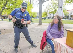  ?? GABRIELA CAMPOS/THE NEW MEXICAN ?? Officer Joshua McDermott jokes with Michele Chisholm on Friday about his affinity for dancing with a group of young break dancers who frequent the Plaza.