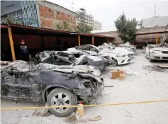  ??  ?? A police officer stands next to cars destroyed in an earthquake. — Reuters photo