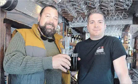  ?? MELINDA CHEEVERS METROLAND ?? Olde Angel Inn manager Peter Ault, right, raises a straw-free glass with Tim Bala. The Niagara-on-the-Lake pub has stopped offering plastic straws to customers in an effort to reduce plastic waste.