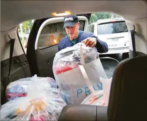  ?? Christian Abraham/Hearst Connecticu­t Media ?? Matt McMahon, coordinato­r for the town of Wilton's Toys for Tots program, loads his vehicle Wednesday with hats knitted by Linda Bracken at the senior housing complex she lives at in Norwalk.