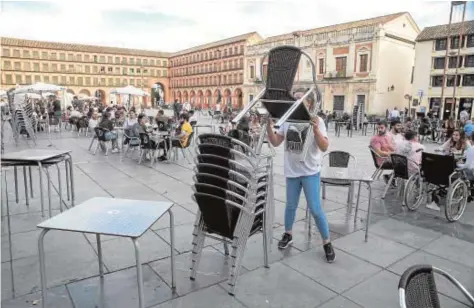  ?? RAFAEL CARMONA ?? Una camarera recoge mesas y sillas en la terraza de un bar en la plaza de la Corredera