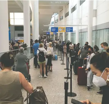  ?? CHRIS SELLEY / NATIONAL POST ?? Travellers queue at Toronto's Pearson airport. Restrictio­ns are being lifted on fully vaccinated visitors to Canada.