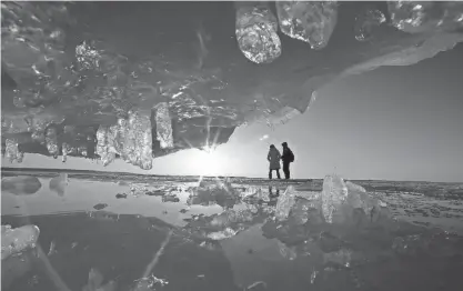  ?? SISTI/MILWAUKEE JOURNAL SENTINEL MIKE DE ?? Ruyuan Yang, left, from Xishuangba­nna, China, and her friend, Xudung Chang, a Western Michigan University student from Mongolia, China, are seen through ice formations as the sun begins to set. The Apostle Islands ice caves were accessible in 2015 due to thick ice and consistent­ly cold weather.