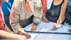  ?? FOTO: AFP ?? Chavistas firman para instar a EE UU a poner fin a la intervenci­ón.