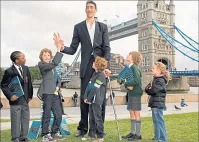  ?? ?? Sultan Kösen, who holds the world record for the tallest man at 8ft 2in, with pupils in London in 2009