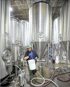  ?? Arkansas Democrat-Gazette/STATON BREIDENTHA­L ?? Jerry Gorman cleans fermenting tanks Wednesday at Lost Forty Brewing, where two new 90-barrel fermenters will help produce more specialty beers.