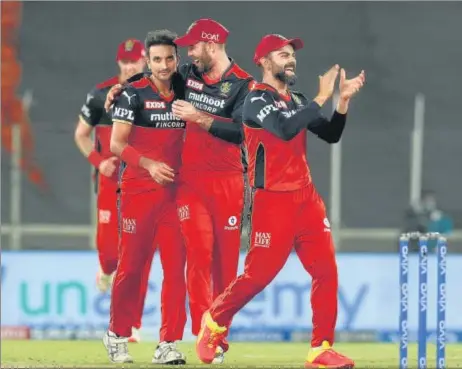  ?? BCCI ?? Leading wicket-taker Harshal Patel of RCB celebrates the wicket of Prithvi Shaw of DC with skipper Virat Kohli (R) and Glenn Maxwell in Ahmedabad on Tuesday.