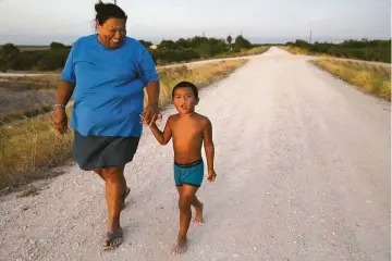  ?? Jerry Lara photos / Staff photograph­er ?? Elsa Jackson, 42, walks with her son Abraham Josiah, 4, on the levee by their land in a Lower Rio Grande Valley community that takes up both sides of the levee along the border.