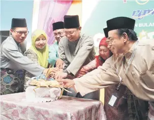  ??  ?? PENGHUJUNG SYAWAL: Abdullah memotong ketupat pada Majlis Gawai Raya di RTM Kuching. Turut kelihatan, Jamel (kiri) dan Faridah (dua kiri).