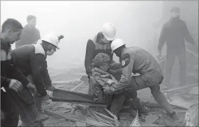  ?? [SYRIAN CIVIL DEFENSE WHITE HELMETS] ?? Civil defense workers carry a wounded man after airstrikes hit a rebel-held suburb Thursday near Damascus, Syria.