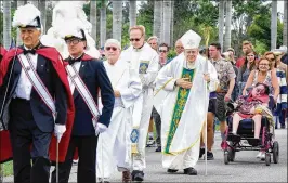  ?? MELANIE BELL / THE PALM BEACH POST ?? The Rev. Gerald Barbarito (center right), bishop of the Palm Beach Diocese, walks in a procession to the veterans memorial after the Mass. “This is always a wonderful crowd that comes out for Memorial Day Mass,” he said.