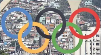  ?? JAMES LANG, USA TODAY SPORTS ?? The Olympic rings can’t hide the squalor of the favelas in the background at the 2016 Summer Olympic Games in Rio de Janeiro.