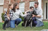  ?? NATI HARNIK/ASSOCIATED PRESS ?? Kim Simeon with husband Adam and children, Annabel, 9, and Brennan, 11, kneel with Nala, a dog they are fostering at their home in Omaha, Neb. Shelters across the country are reaching out for volunteers to help temporaril­y care for animals, and they’ve seen a record response.