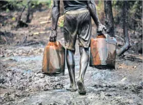  ?? Photo: Akintunde Akinleye/Reuters ?? Oil bunkering: A man works at an illegal oil refinery near the Nun River in Nigeria’s oil state of Bayelsa.