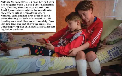  ?? ?? Natasha Stepanenko, 43, sits on her bed with her daughter Yana, 11, at a public hospital in Lviv, Ukraine, Saturday, May 15, 2022. On April 8, a missile struck the train station in the eastern city of Kramatorsk where Natasha, Yana and her twin brother Yarik were planning to catch an evacuation train heading west and, they hoped, to safety. Yana lost two legs, one just above the ankle, the other higher up her shin. Natasha lost her left leg below the knee.