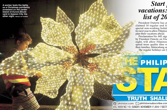  ?? MIGUEL DE GUZMAN ?? A worker tests the lights on a Christmas poinsettia ornament on the center island of Aurora Boulevard in Quezon City the other night.