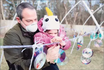  ?? Jarret Liotta / Hearst Connecticu­t Media ?? Michael Dwork, of Westport, helps his daughter Lottie, 3, hang her decoration at the Winter Outdoor Lights Festival at MoCA Westport on Saturday.