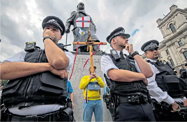  ??  ?? Police guard the bronze sculpture of Winston Churchill in Parliament Square, London, after it was defaced during a Black Lives Matter protest on Sunday