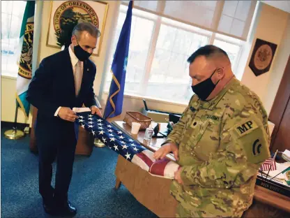  ?? Tyler Sizemore / Hearst Connecticu­t Media ?? U.S. Army National Guard Lt. Col. Sean O’Donnell delivers a American flag flown in Kuwait to First Selectman Fred Camillo at Town Hall in Greenwich on Tuesday. O’Donnell, a Greenwich police officer and 31-year veteran of the National Guard, recently returned from Kuwait and brought back a flag flown at the Camp Arifjan military base.