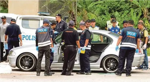  ?? BERNAMA PIC ?? Forensic officers checking the vehicle that was used by the three robbers yesterday.