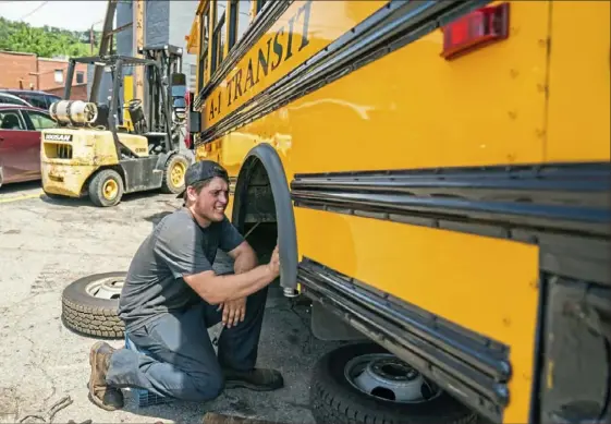 ?? Andrew Rush/Post-Gazette photos ?? Mechanic Rob Stinson with A-1 Transit prepares a bus for the new school year outside the garage in Lawrencevi­lle on Friday. If any part of the city schools’ proposed plan does not move forward, thousands of students may be left without a ride on the first day of school.