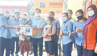  ??  ?? SERAH: Jonathan (kanan) menyerahka­n bantuan solar kepada salah seorang penerima warga emas dari Kg.Tinanom sambil disaksikan rombongan daripada Pejabat Parlimen Ranau bersama sebahagian penduduk.